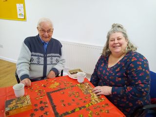 A photo of two people smiling with a puzzle